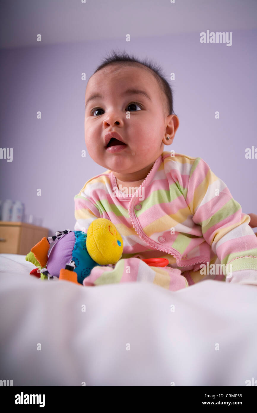 Ein kleines Mädchen wird abgelenkt, während mit ihrem Spielzeug spielen. Stockfoto