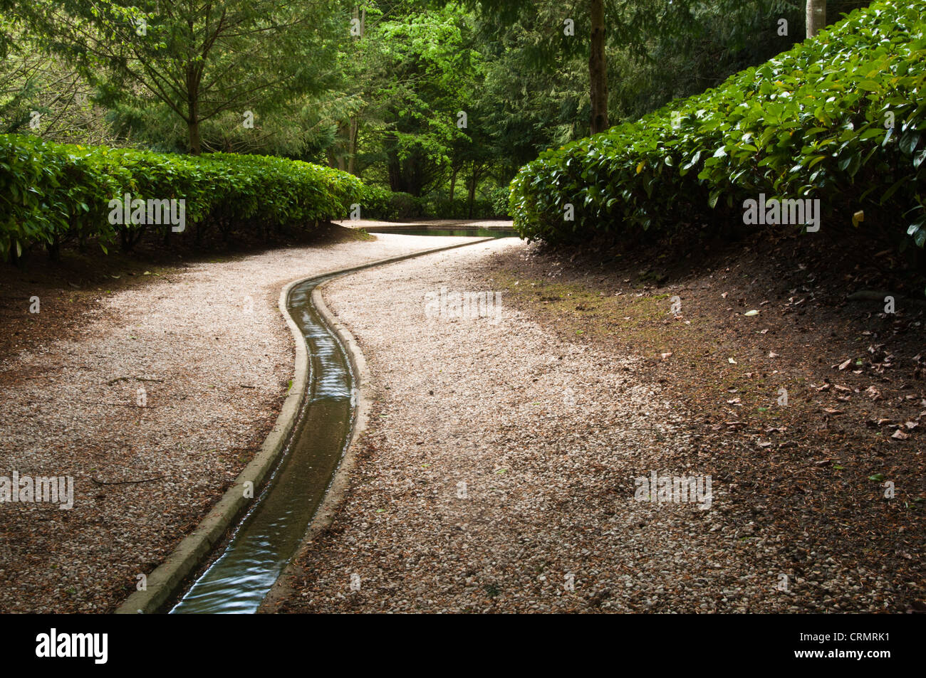 Der Stein gesäumten Bächlein fließt mit klaren Frühjahr Wasserschlangen seinen Weg in Richtung kaltes Bad in der wässrigen Walk Rousham House, Oxfordshire, England Stockfoto
