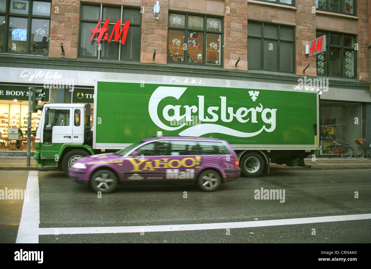 Carlsberg A LKW und ein Auto von Yahoo im Verkehr Stockfoto