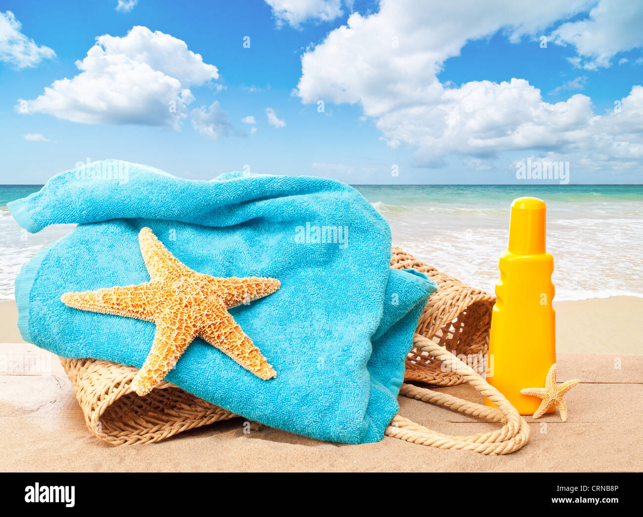 Urlaub Strandkorb mit Handtuch und sun Tan Lotion mit Blick auf eine idyllische Sandstrand Stockfoto