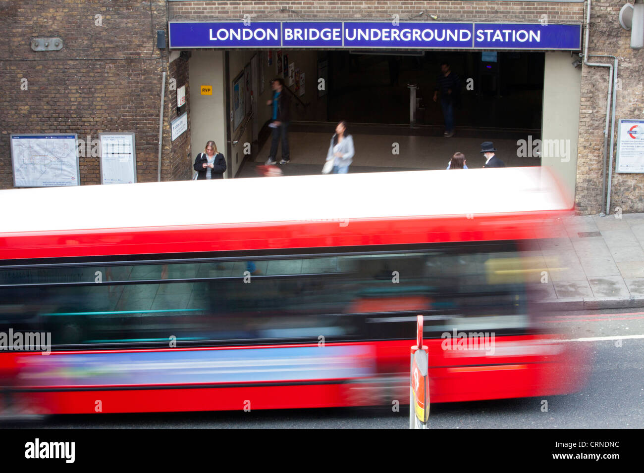 Einem roten Londoner Bus vorbei an einen Eingang zur U-Bahn-Station London Bridge. Stockfoto