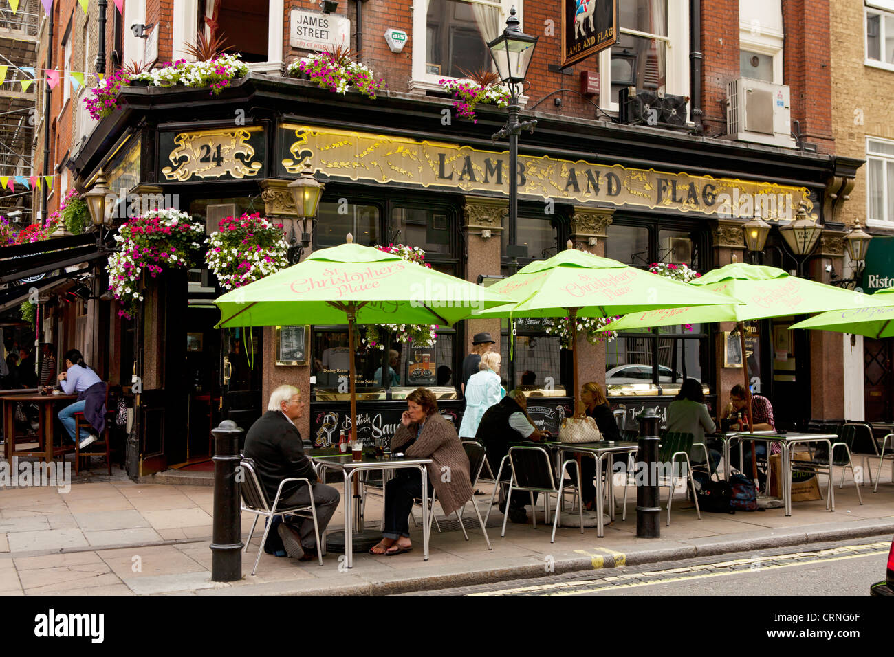 Menschen sitzen unter den Sonnenschirmen vor dem Lamm und Fahne Pub in der James Street. Stockfoto
