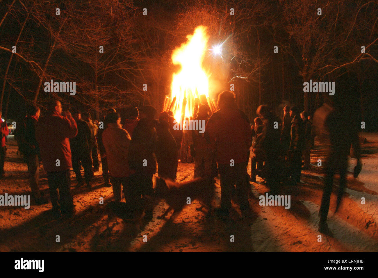 Menschen um ein Lagerfeuer beim Feiern Stockfoto