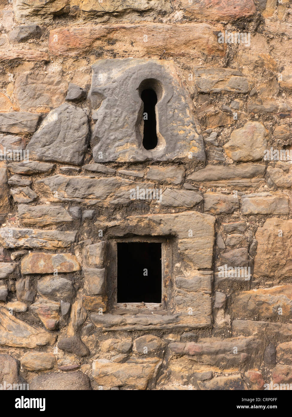 Details ein Schlüsselloch Fenster und kleinen vergitterten Fenster in einer Burgruine Stein schottischen. Stockfoto
