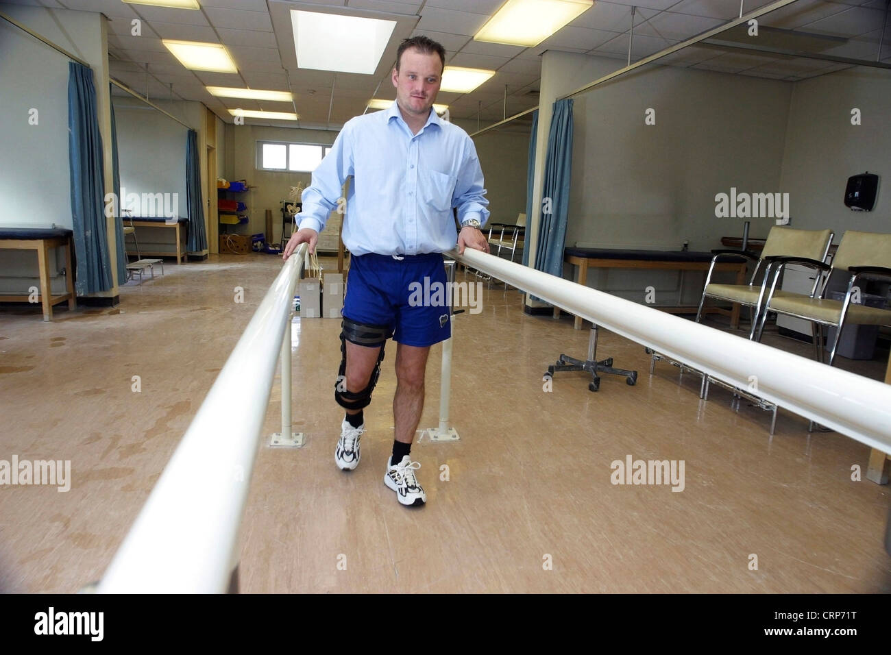 Ein männlicher Patient mit einer rechten Bein Donjoy Prothese gehen mit der Unterstützung von einem Handlauf ausgestattet. Stockfoto