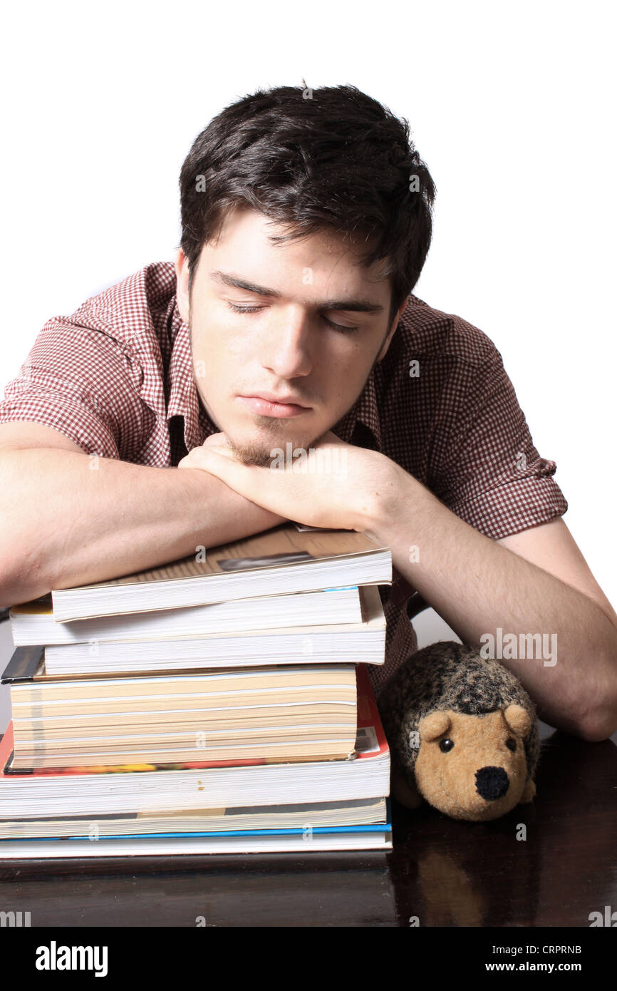18 Jahre alter Mann schlafen auf Schulbücher beim Sitzen am Schreibtisch Stockfoto
