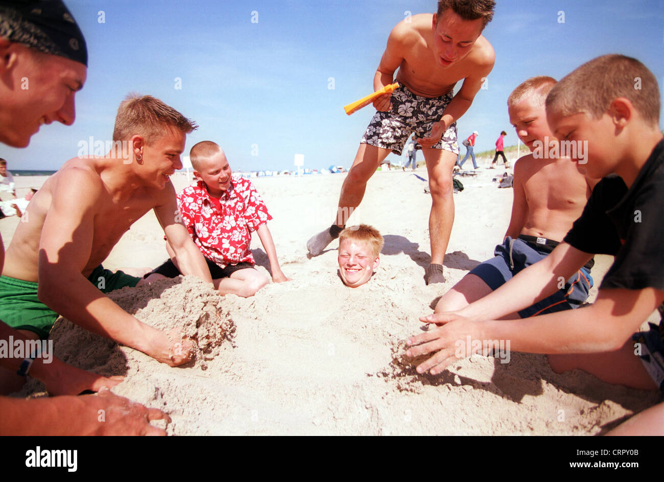 Ein Junge steckt bis zum Hals in Sand eingebuddelt Stockfoto