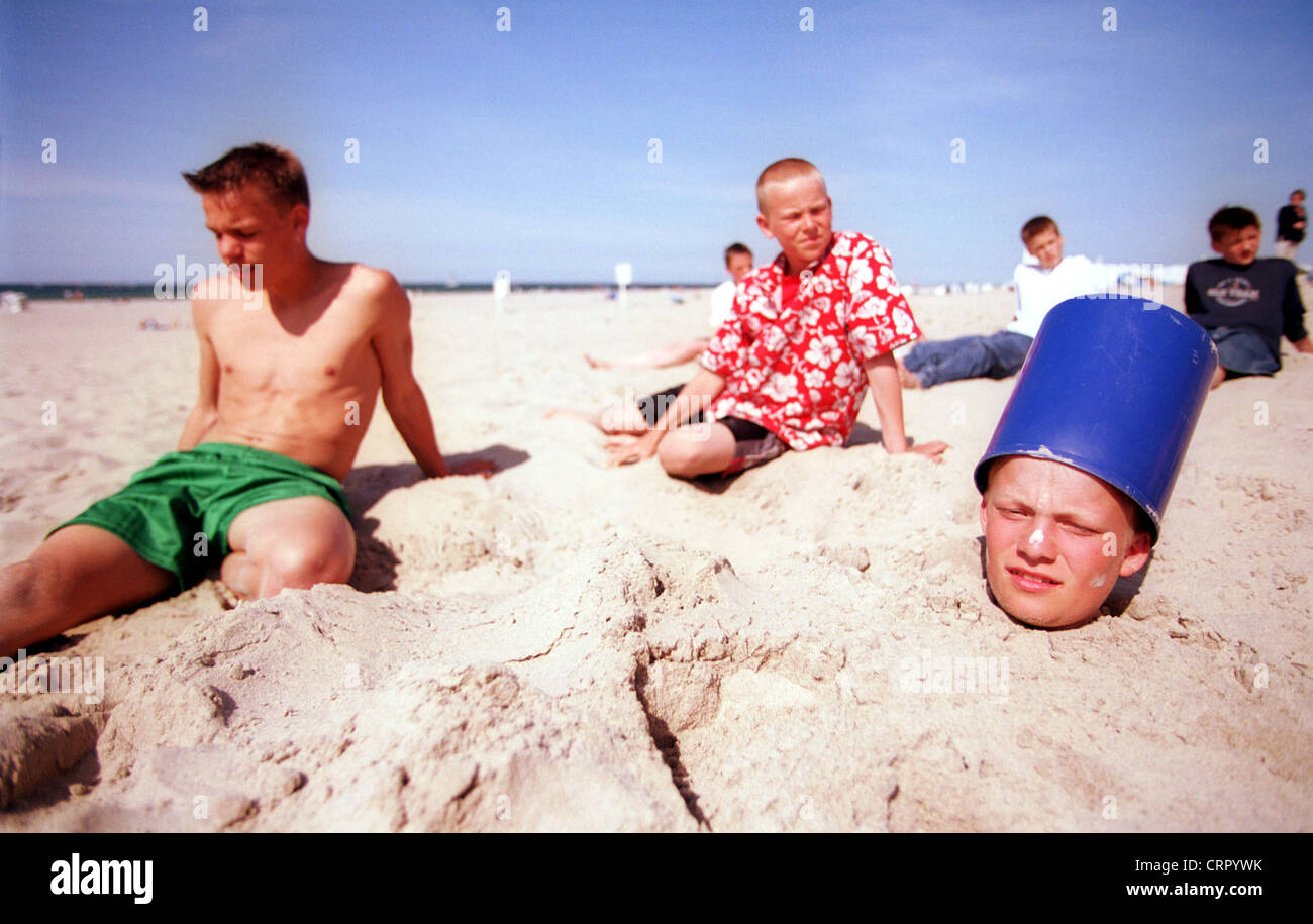 Ein Junge steckt bis zum Hals in Sand eingebuddelt Stockfoto