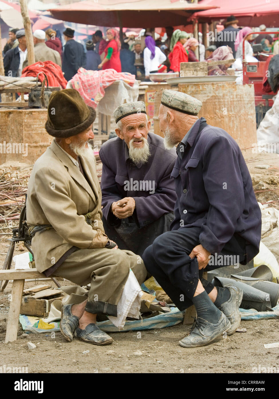 Ältere Uyghur chinesische Männer in traditioneller Kleidung auf dem lokalen Markt in der kleinen Stadt von Upal in China. Stockfoto