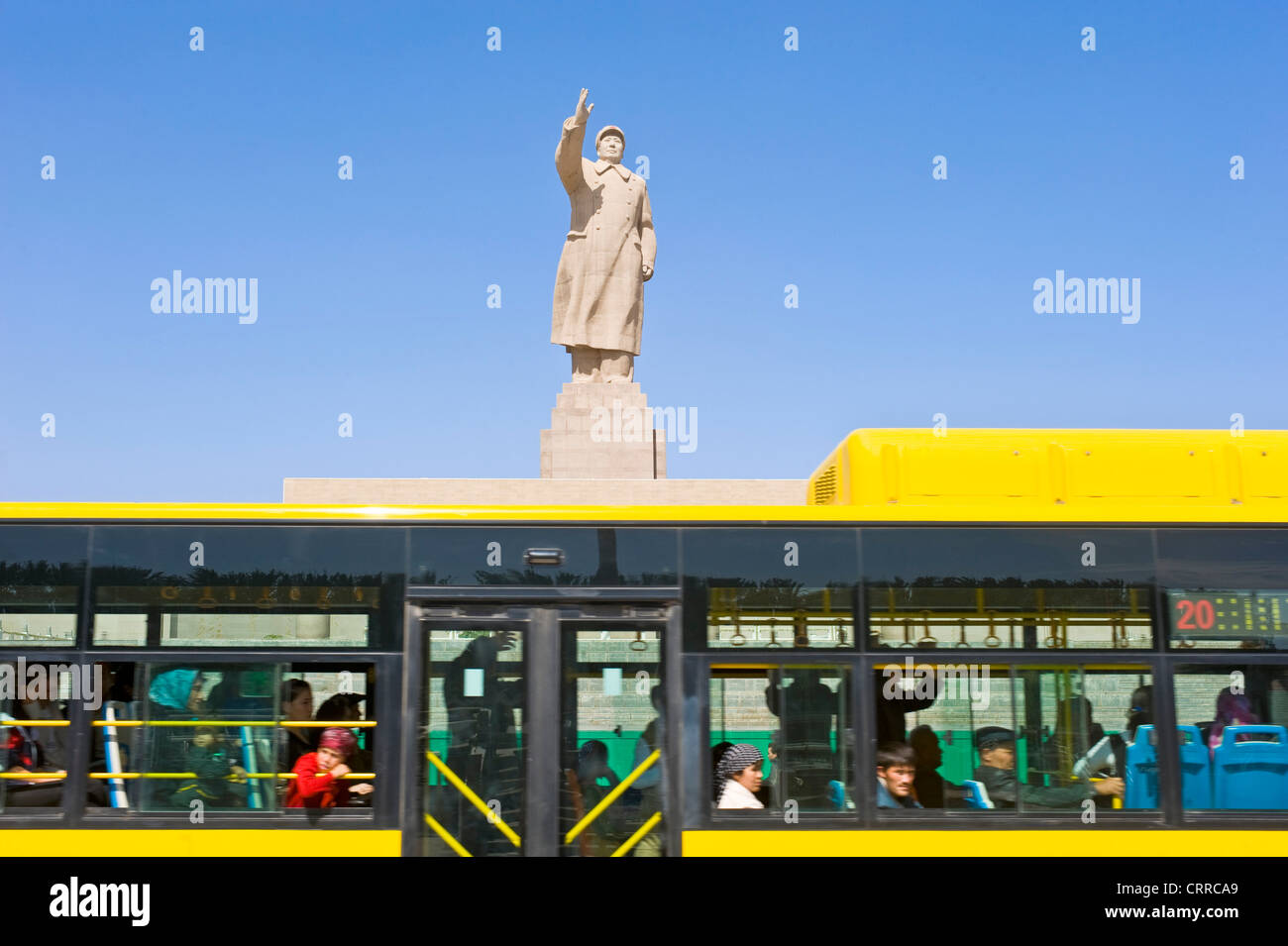 Mit Bewegungsunschärfe.  Ein öffentlicher Bus fährt vorbei an der Statue von Mao Zedong gegenüber dem Stadtplatz in Kashgar. Stockfoto