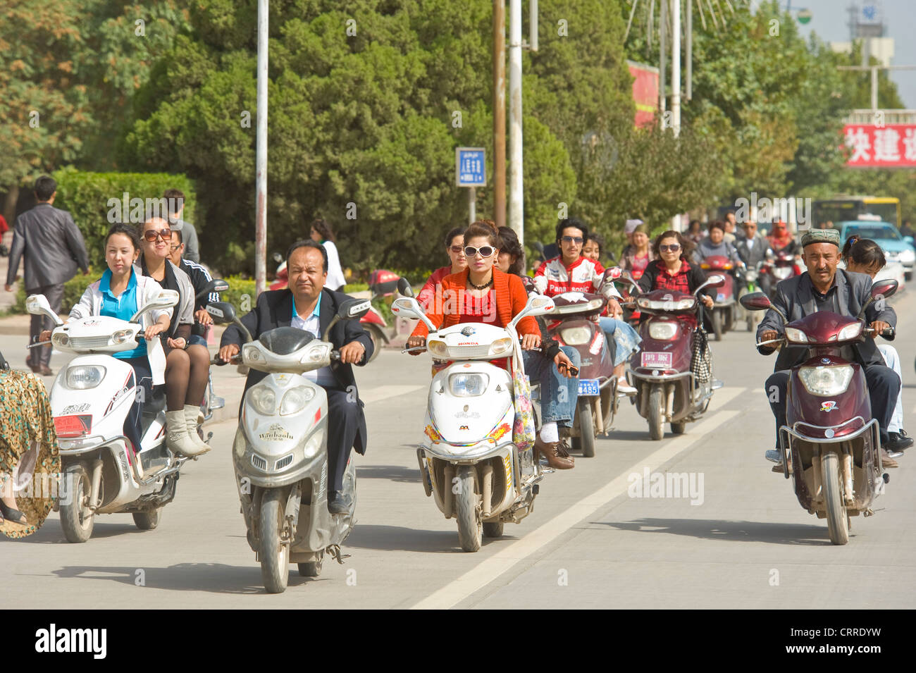 Eine komprimierte perspektivische Ansicht des Menschen auf Roller unterwegs an einer Hauptstraße in Kashgar. Stockfoto