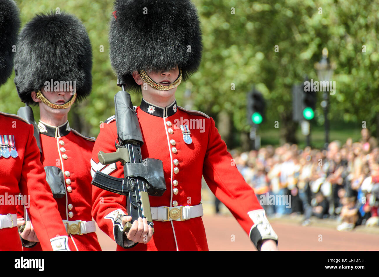 Grenadierwache Nahaufnahme des Wachwechsels am Buckingham Palace London | LONDON, Vereinigtes Königreich — Eine Grenadierwache marschiert aus nächster Nähe während des Wachwechsels am Buckingham Palace, sein SA80-Gewehr im Winkel und Kampagnenmedaillen sichtbar auf seiner Uniform. Das weiße Sternkragenabzeichen identifiziert speziell die Grenadierwachen — jedes der fünf Fußgarderegimenter trägt ein eigenes Kragenabzeichen und platziert die Knöpfe seiner Uniform unterschiedlich, der primäre visuelle Code, der sie in der Zeremonienuniform unterscheidet. Stockfoto