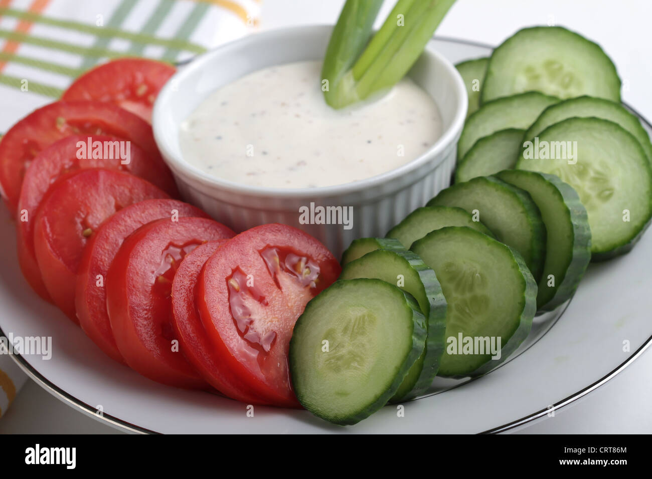 Ein Teller mit Roma Tomatenscheiben und kernlose Gurken mit einer Ranch Dressing eintauchen. Stockfoto