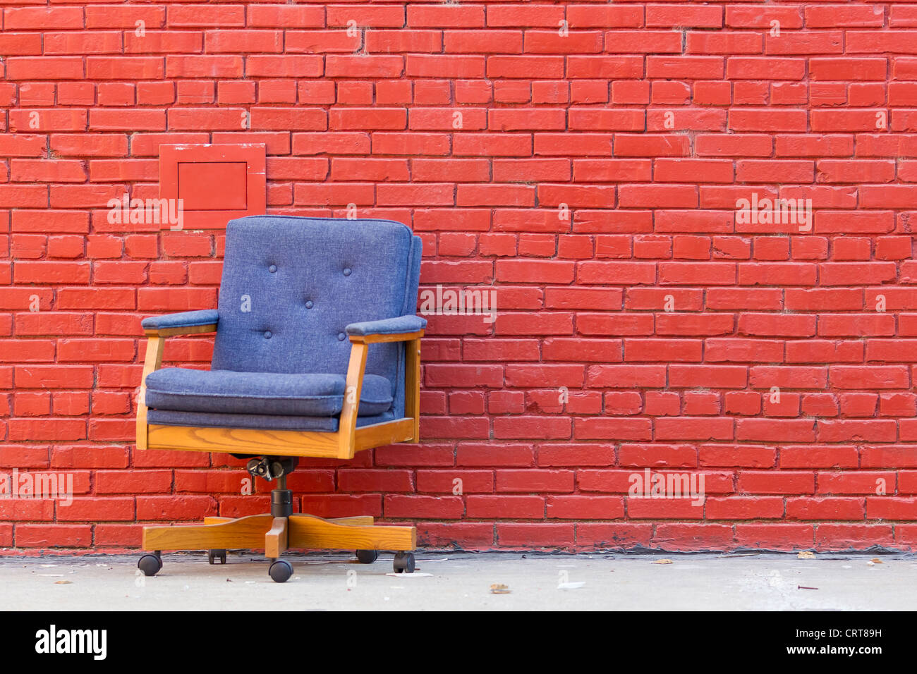 Bürostuhl außen gegen eine Red brick wall Stockfoto
