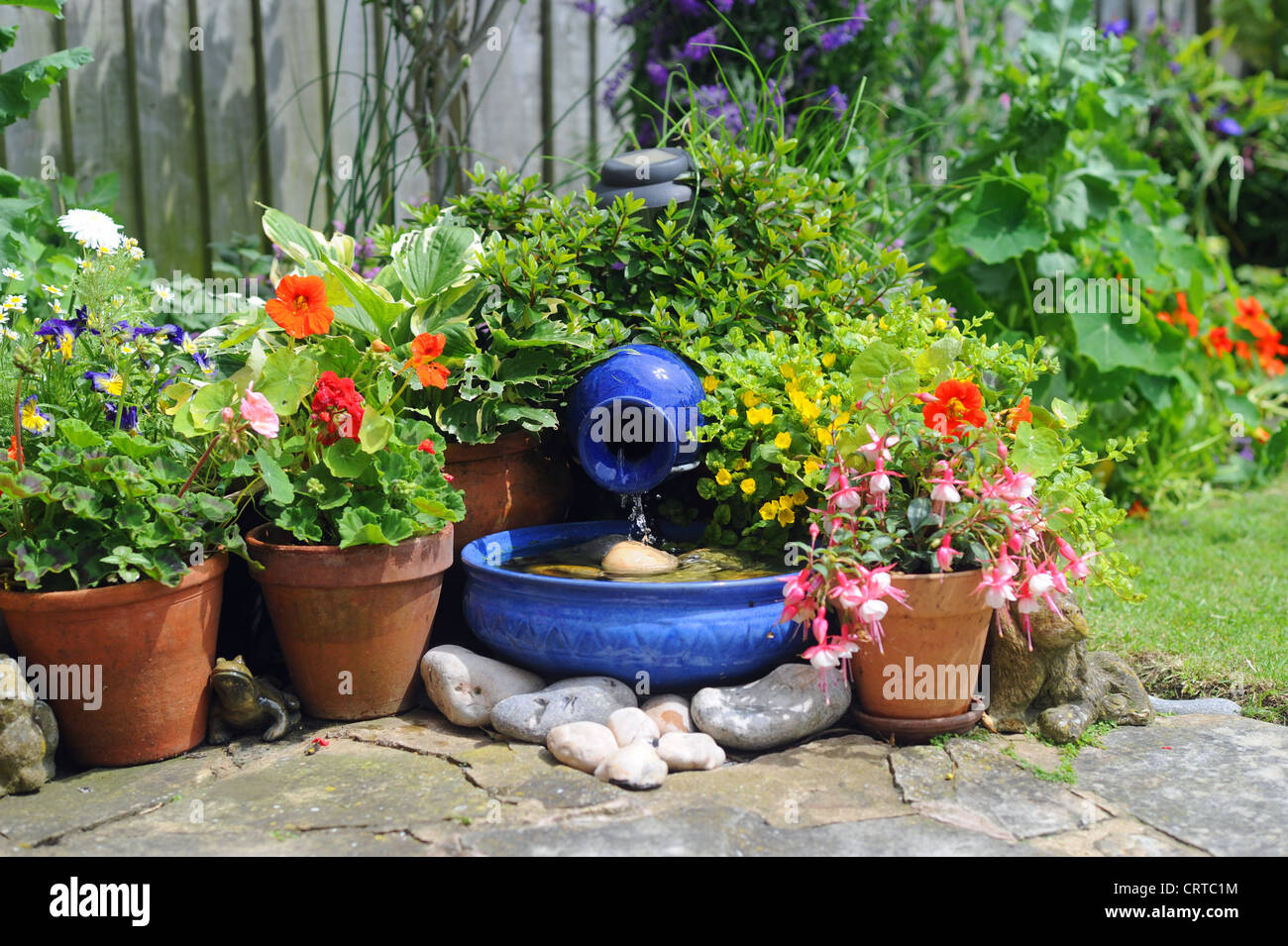 Solar powered Garten Funktion blau Wasserschale durch Topfpflanzen UK Stockfoto