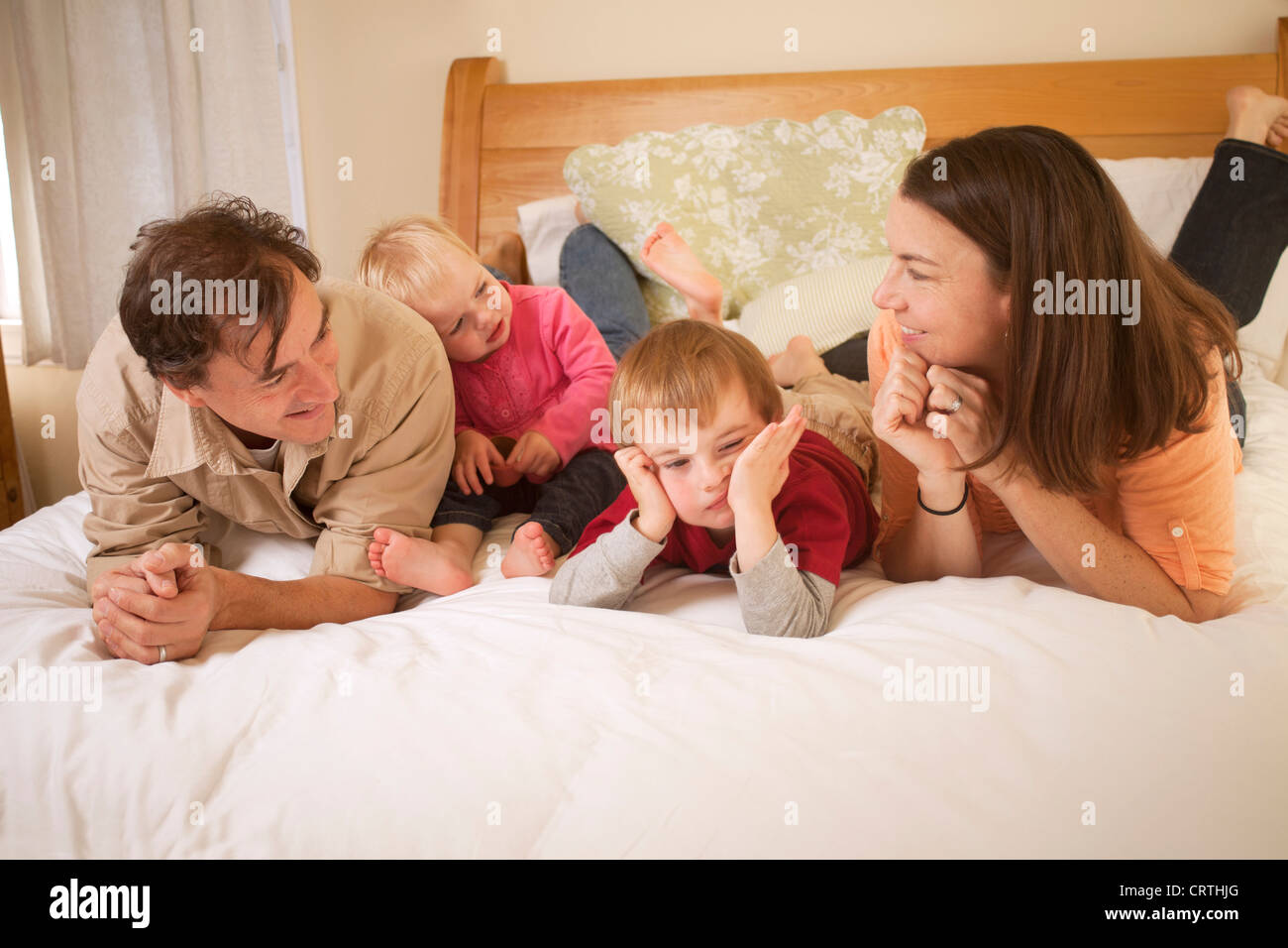 Mutter, Vater und zwei Kinder sind auf dem Bett liegend. Stockfoto