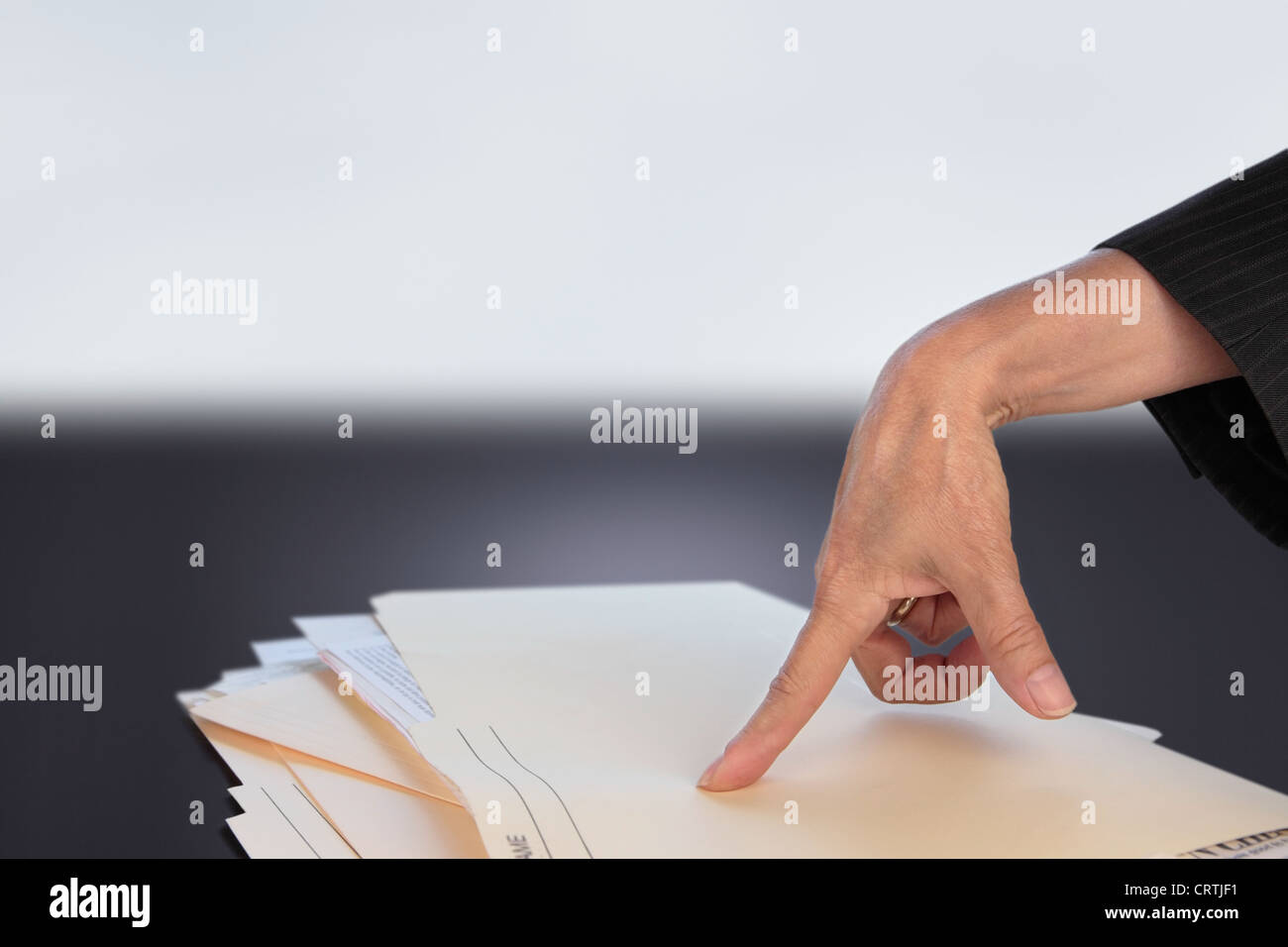 die Hand einer Frau zeigt auf einen Haufen von Dateien Stockfoto