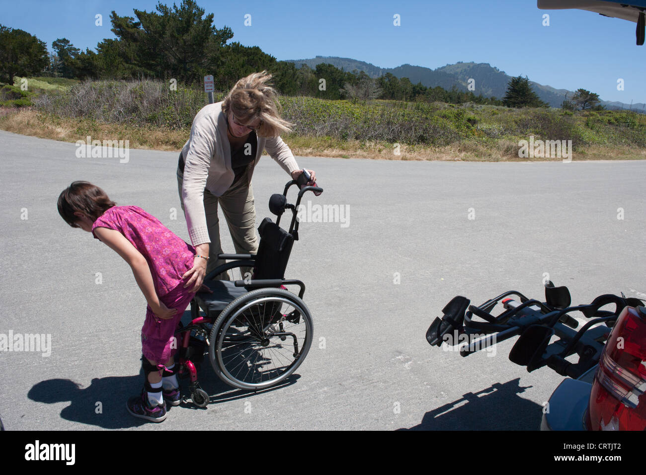 Mama hilft ihre sieben Jahre alte Tochter mit Muskeldystrophie sitzen in ihrem Rollstuhl Natur auf einer Wanderung in Nord Kalifornien zu gehen. Stockfoto