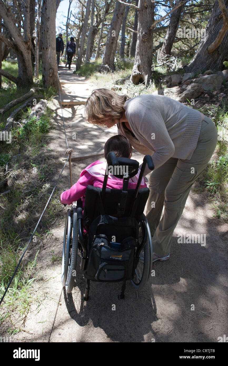 Mutter Tochter während einer Wanderung mit Muskeldystrophie Schritt aus dem Rollstuhl zu helfen.  Kalifornien, USA Stockfoto
