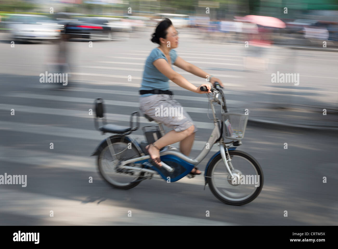 Reiten einer elektrischen Batterie angetrieben Fahrrad in gehobenen Einkaufsviertel Sanlitun in Beijing, China. Stockfoto