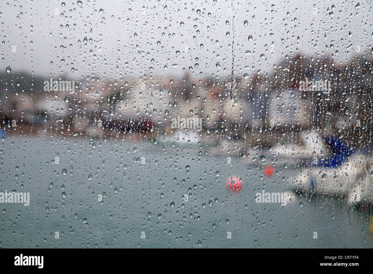 Regentropfen an den Fenstern der Fähre nach Herm mit Blick auf Hafen von St Peter Port, Guernsey Stockfoto