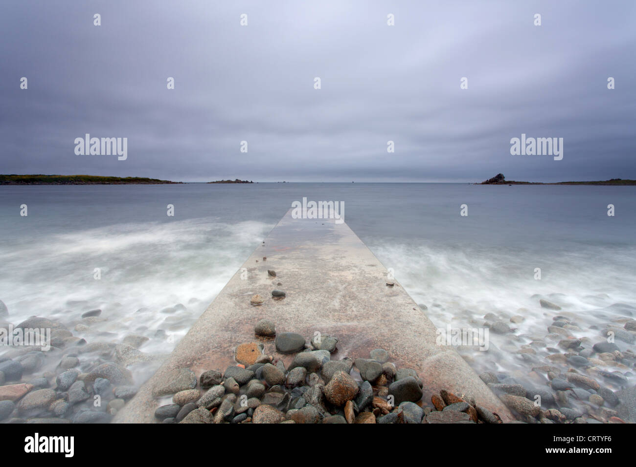 Baie des Pequeries Wellen Waschen über Wellenbrecher Guernsey, Kanalinseln, UK Stockfoto