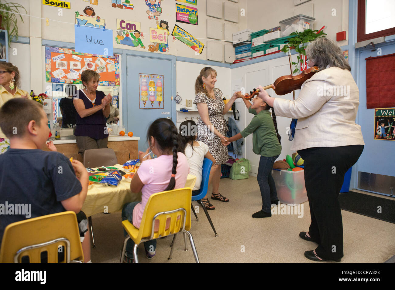 Rektor einer Grundschule spielt Violine für einen gemischten Altersgruppen Heilpädagogische Klassenzimmer zu feiern. Stockfoto