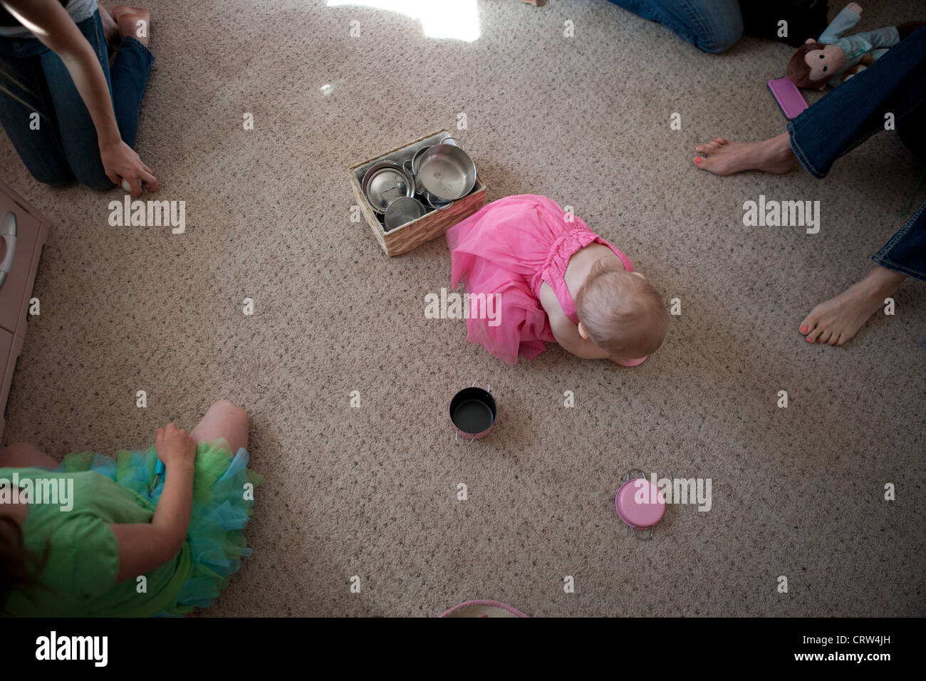 Zwölf Monate altes Mädchen spielen auf dem Boden ihres Wohnzimmers mit Miniatur-Töpfe und Pfannen, erhöhte Ansicht. Stockfoto