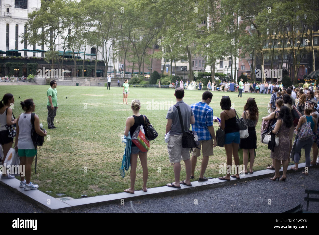 Leute warten zu dürfen, sich hinzusetzen für Sommer Kinoleinwand im Bryant Park, Manhattan, New York Stockfoto