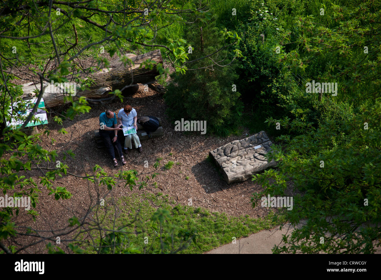 Ein paar sitzt zwischen den Bäumen und künstlerische Installationen in Kew Gardens in London. Stockfoto