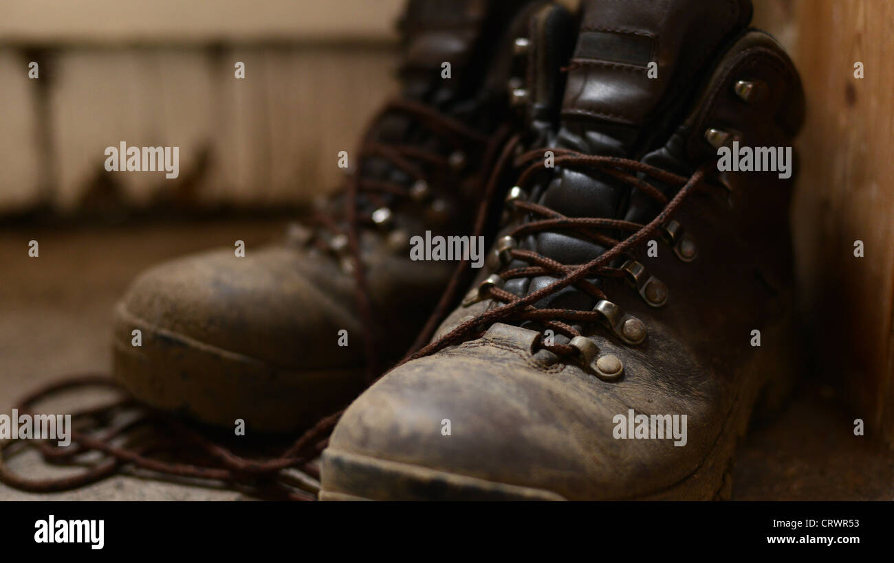 Schlammigen Wanderstiefel Stock neben eine alte verwitterte Tür Stockfoto