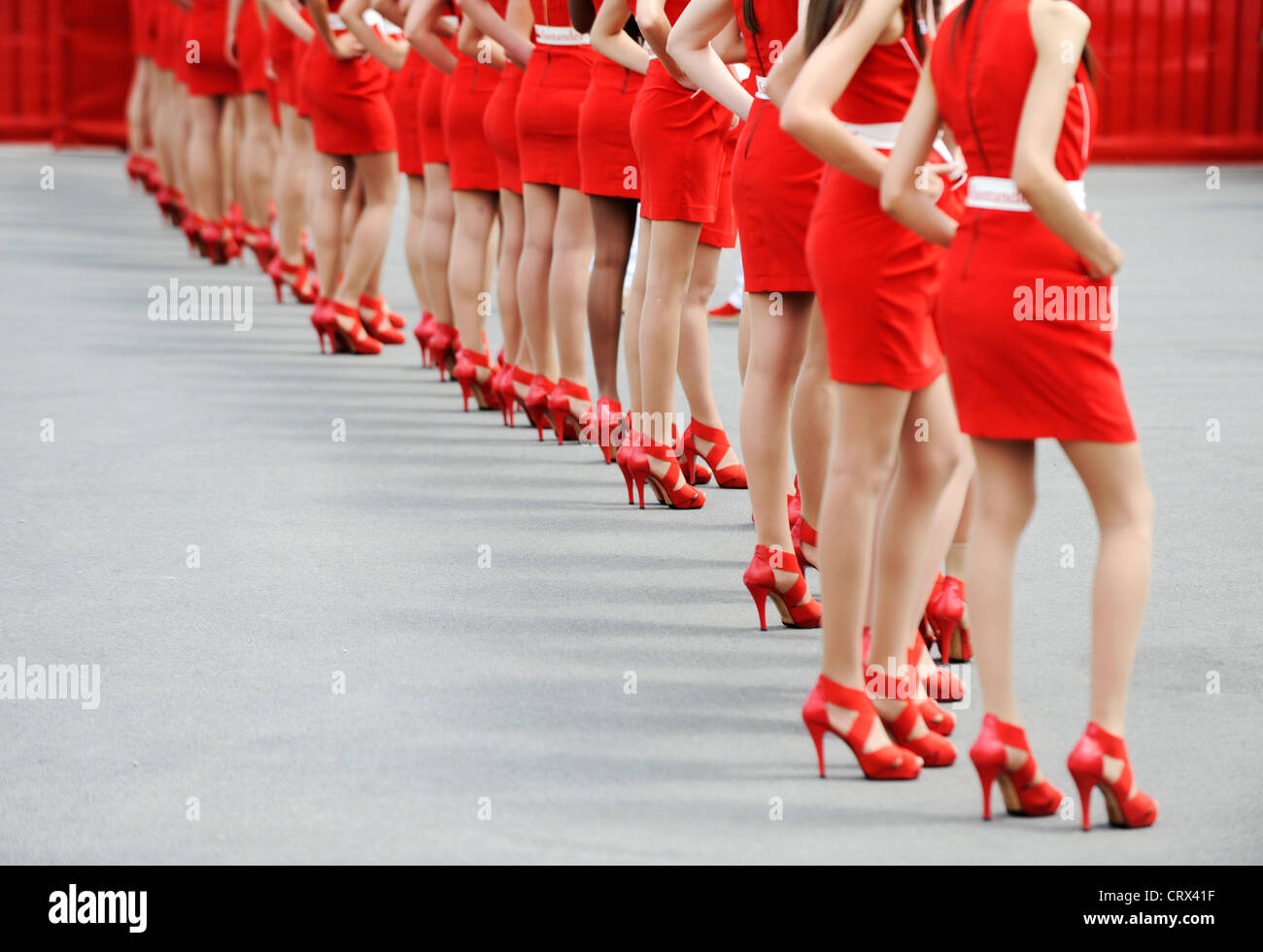Frauen tragen rote Kleider und rote Schuhe mit hohen Absätzen stehen in einer Reihe Stockfoto