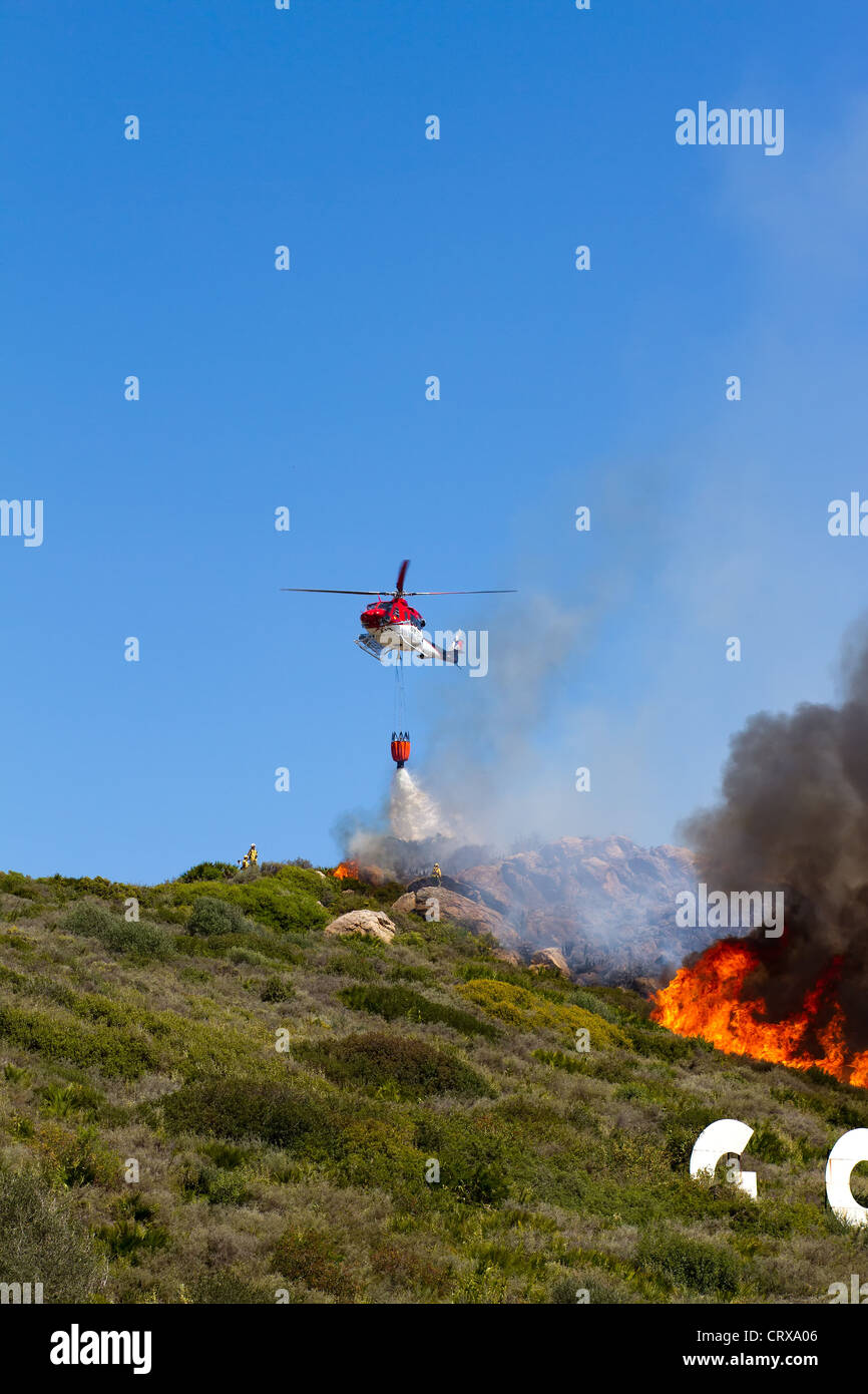 Puerto Duquesa, Costa Del Sol, Spanien; Ein Bush-Feuer brennt am Hang. Emergencu Hubschrauber begießen die Flammen Stockfoto