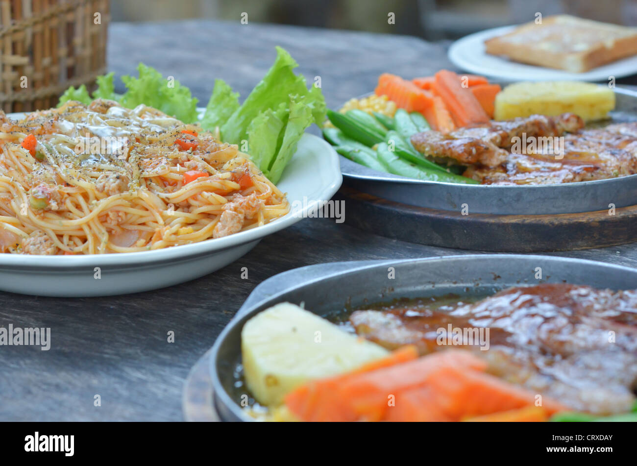 Rindersteak, Schweinesteak und Spaghetti Essen auf Tisch Stockfoto