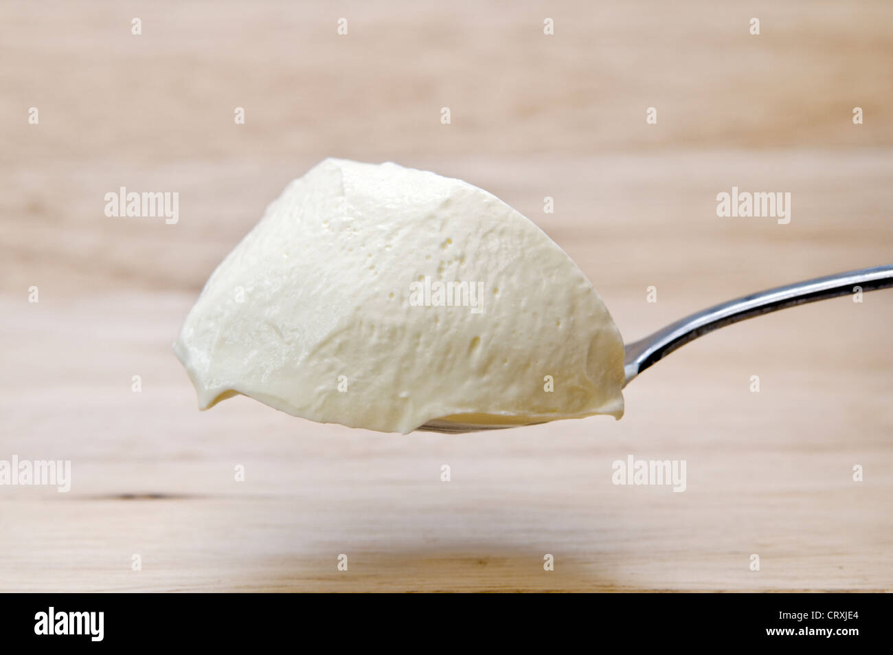 Gehäufte Löffel Creme Fraiche statt über ein Schneidbrett aus Holz Stockfoto