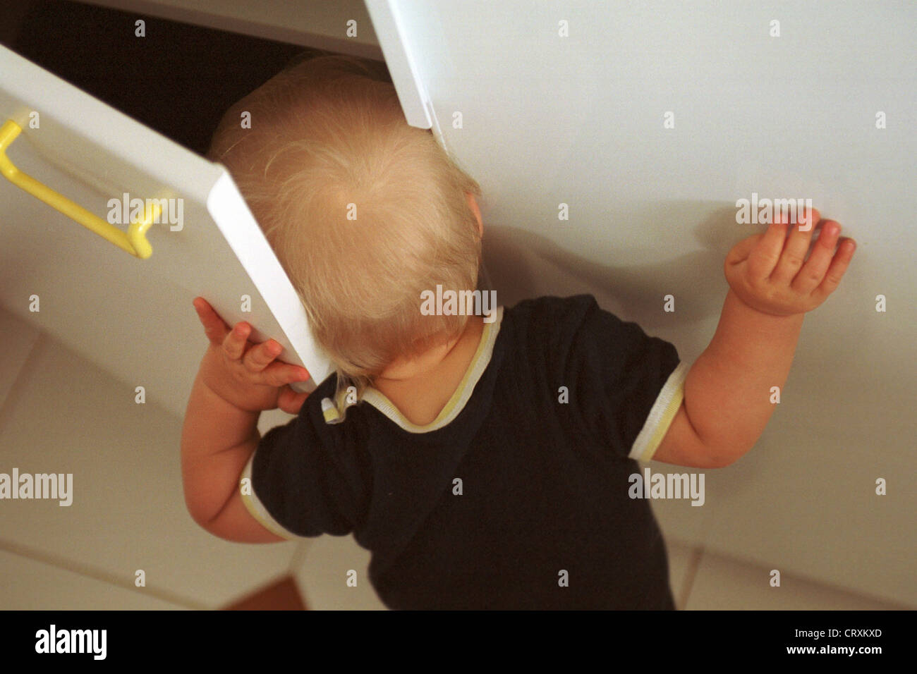 Ein neugieriges Kind steckt seinen Kopf in einen Schaltschrank Stockfoto