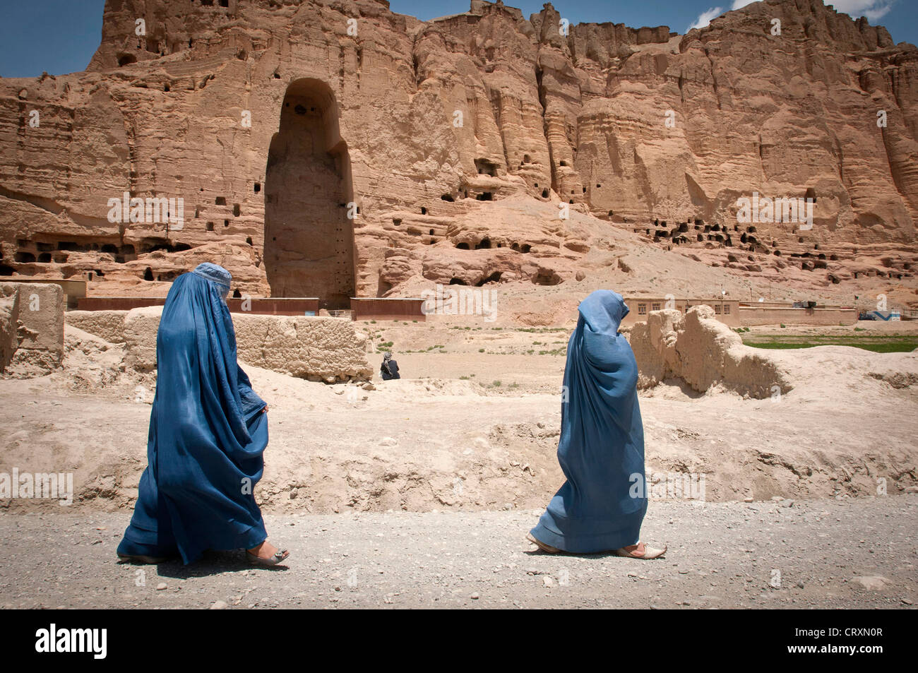 Zwei Frauen gehen vorbei an der riesigen Hohlraum, wo eines alten Buddhas von Bamiyan, bekannt als der "Vater Buddha, früher" stand, 17. Juni 2012 in Bamiyan, Afghanistan. Die monumentalen Statuen wurden 507 – 554 n. Chr. erbaut und waren die größten Statuen von Buddha auf der Erde stehen, bis die Taliban im Jahr 2001 zerstört. Stockfoto