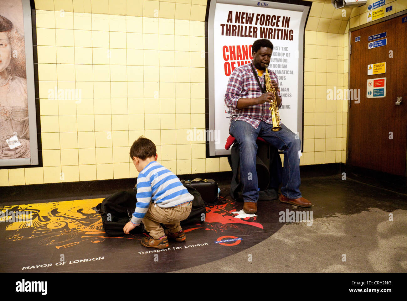 Ein Kind ein Straßenmusikant Geld verleihen, auf der London unterirdisch spielt Saxophon, London UK Stockfoto