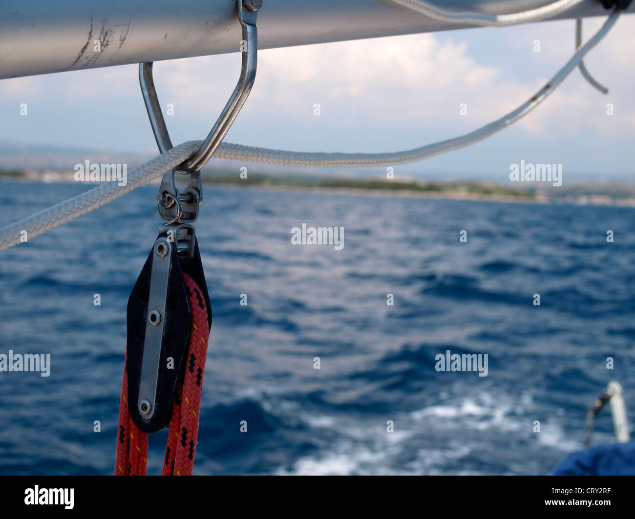 Segelboot-Boom mit Armaturen auf Meer und Küste in Ferne Stockfoto