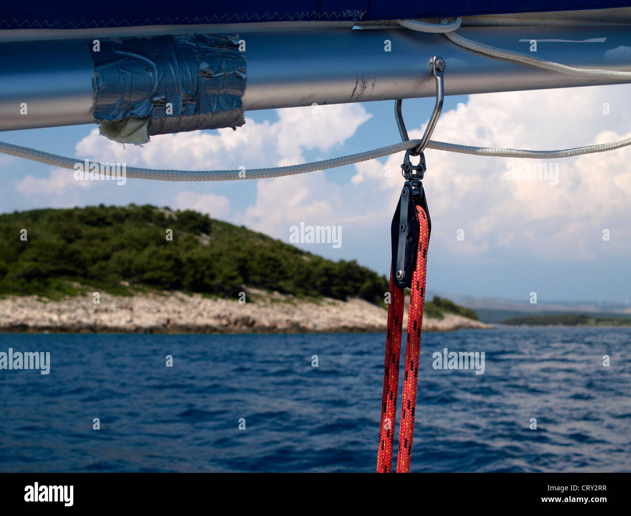 Segelboot-Boom mit Armaturen auf See in der Nähe von Insel hinter Stockfoto
