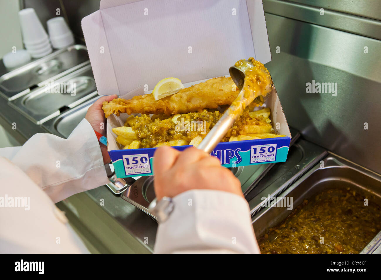 Curry-Sauce, Fish &amp; Chips hinzugefügt wird. Stockfoto