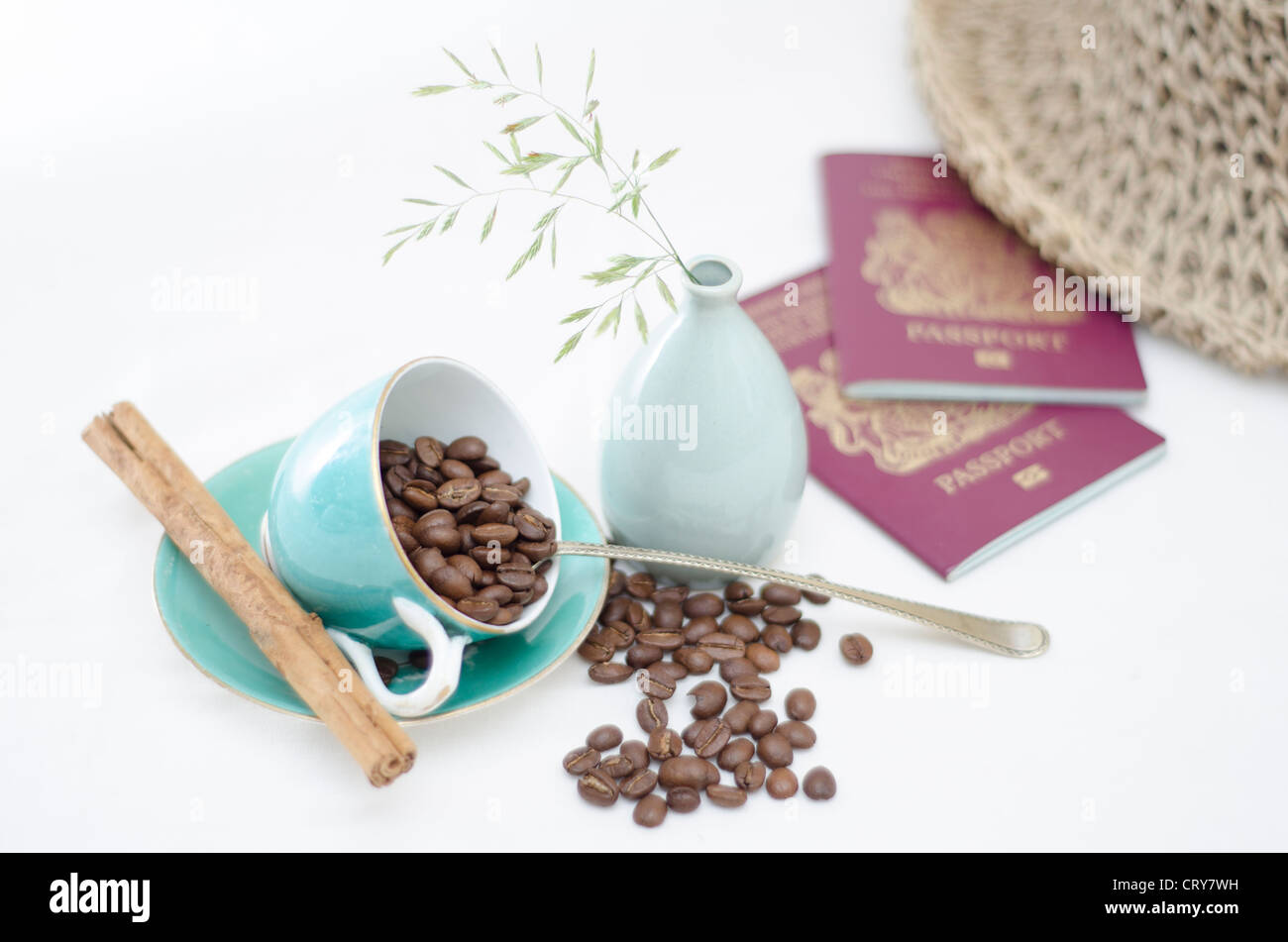 Eine helle Tischplatte Szene mit hellen blauen Kaffeetassen mit Kaffeebohnen und Zimt-stick eine Vase mit zwei britischen Pas Wildgras Stockfoto