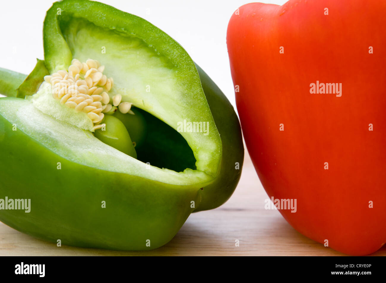 Nahaufnahme von grünen und roten Paprika auf Schneidbrett aus Holz auf einem weißen Hintergrund Stockfoto