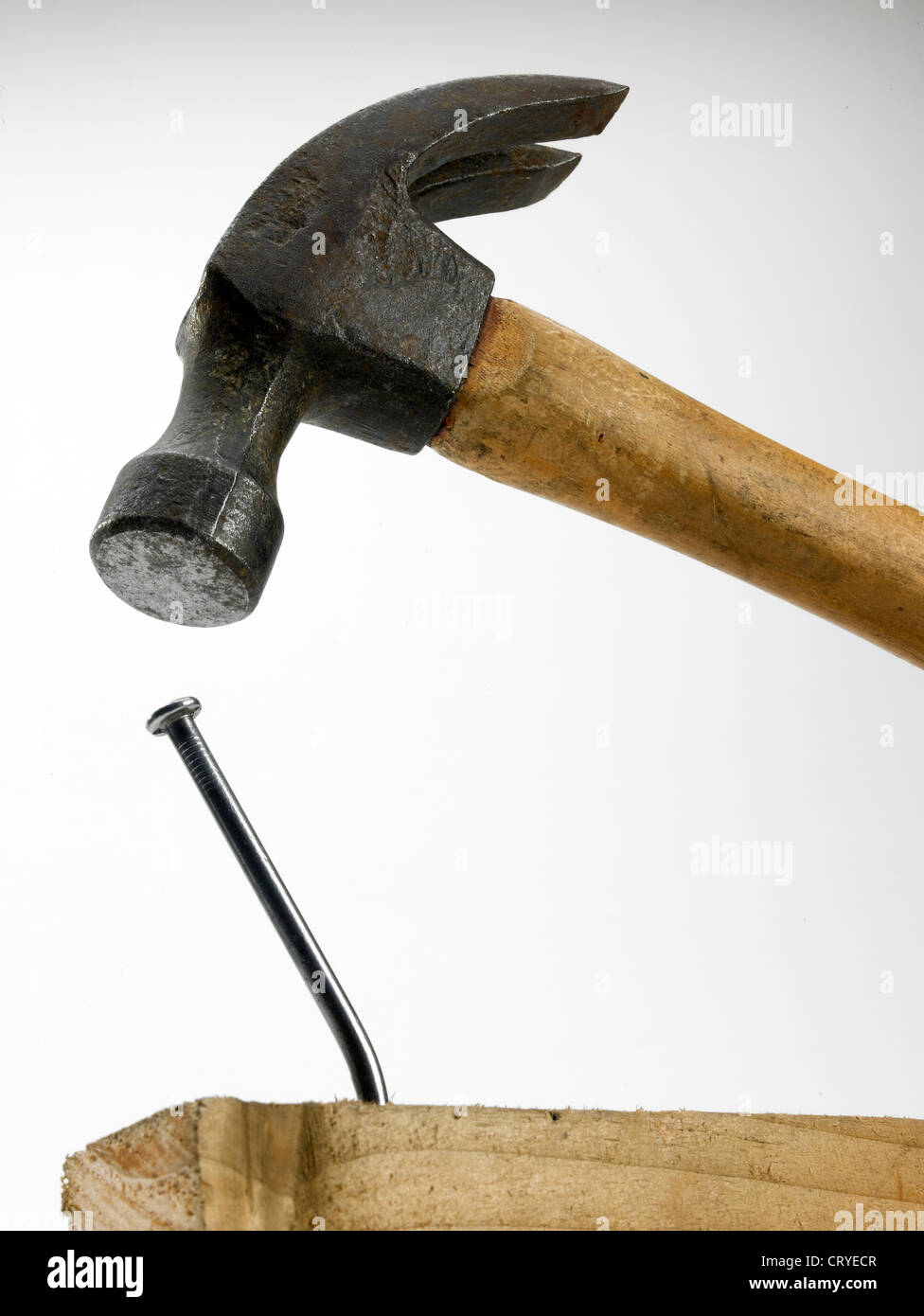 Ein Hammer in unmittelbarer Nähe zum verbogenen Nagel im Holz Stockfoto