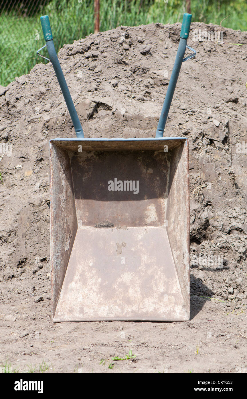 Schubkarre auf dem Hintergrund der Hügel des Sandes Stockfoto