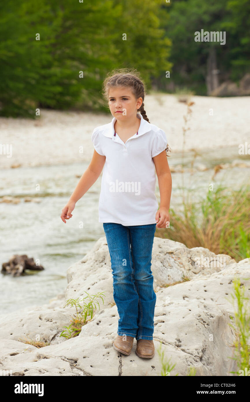 Kleines Mädchen von sieben Jahren in Jeans und weißem Hemd in natürlicher Umgebung Stockfoto