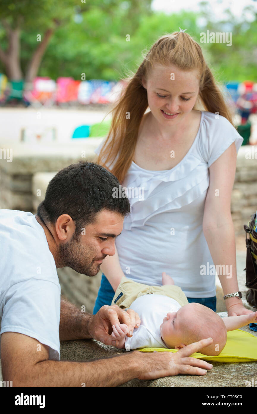 Junge und glückliche Eltern - Vater und Mutter mit ihrem Baby sind dabei, Windeln wechseln Stockfoto