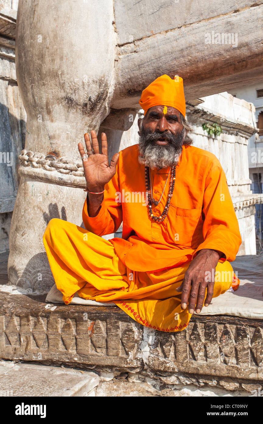 Sadhu, indisch-hinduistischen heiligen Mann gekleidet in traditionellen Safran Roben geben einen Segen für Almosen außerhalb Jagdish Tempel in Udaipur, Rajasthan, Indien Stockfoto
