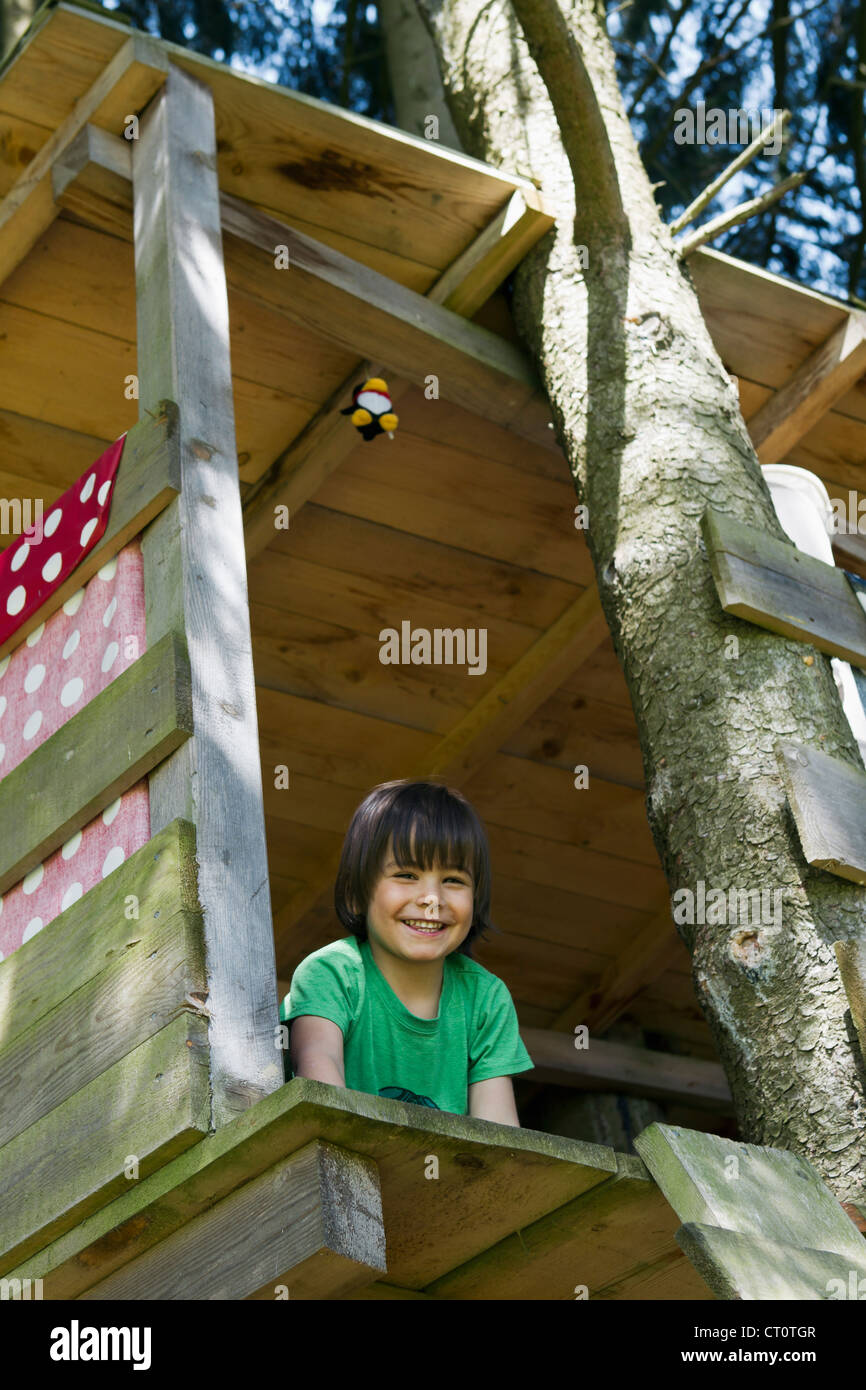 Lächelnde junge sitzt im Baumhaus Stockfoto