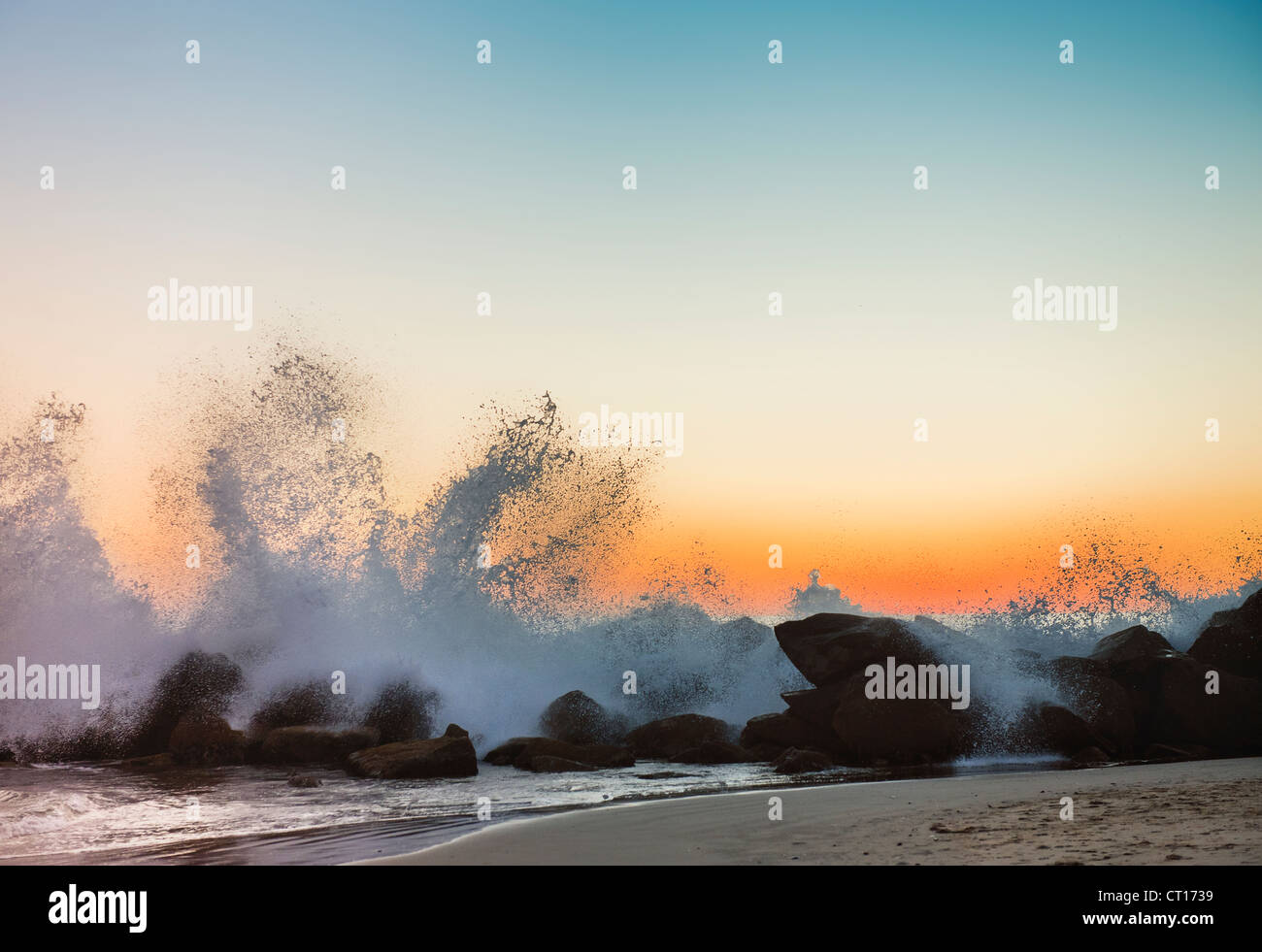 Wellen an der felsigen Strand bei Sonnenuntergang Stockfoto